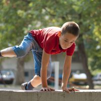 Young boy doing parkour exercise  jumping over wall