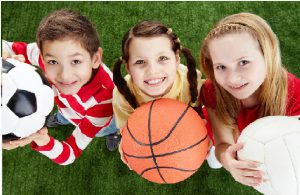 Image of happy friends on the grass with balls looking at camera